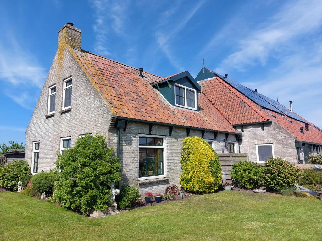 een groot huis met een oranje dak bij Uut in Thuus in Buren