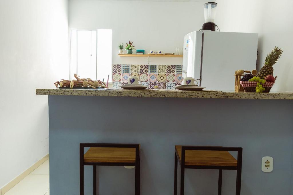 a kitchen with a counter with two stools under it at FLAT TOP COM 02 QUARTOS a 100m da ORLA de ATALAIA na TEMPORADA737 in Aracaju