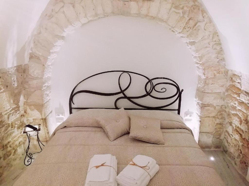 Schlafzimmer mit einem Bett mit schwarzem Kopfteil in der Unterkunft Archetto Bianco in Martina Franca