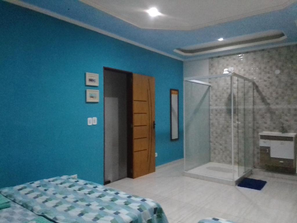 ein Schlafzimmer mit blauen Wänden und einer Glasdusche in der Unterkunft Hospedagem Pousada Fantasia Paraty in Paraty