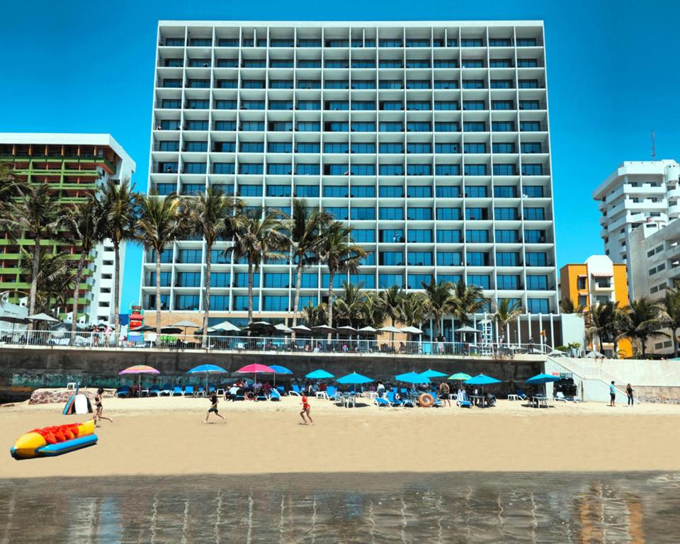 ein Strand mit einem großen Gebäude und Menschen darauf in der Unterkunft Viaggio Resort Mazatlán in Mazatlán