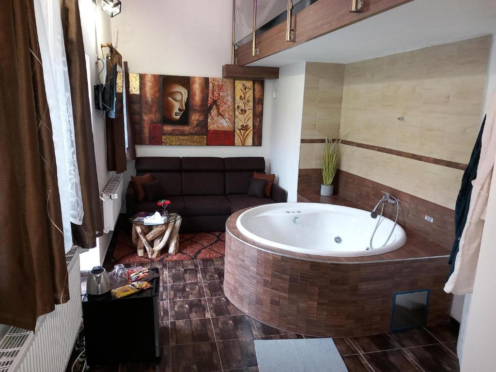 a bathroom with a large tub and a couch at Penzion Vulture Ostrava in Ostrava