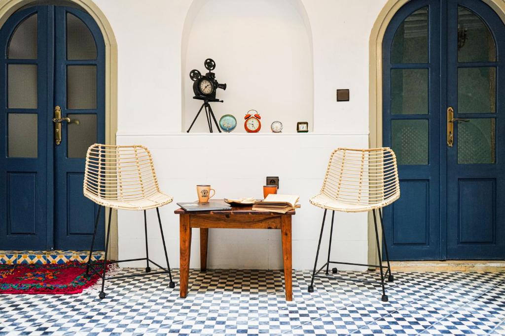 une chambre avec deux portes bleues, une table et deux chaises dans l'établissement DAR44, à Essaouira