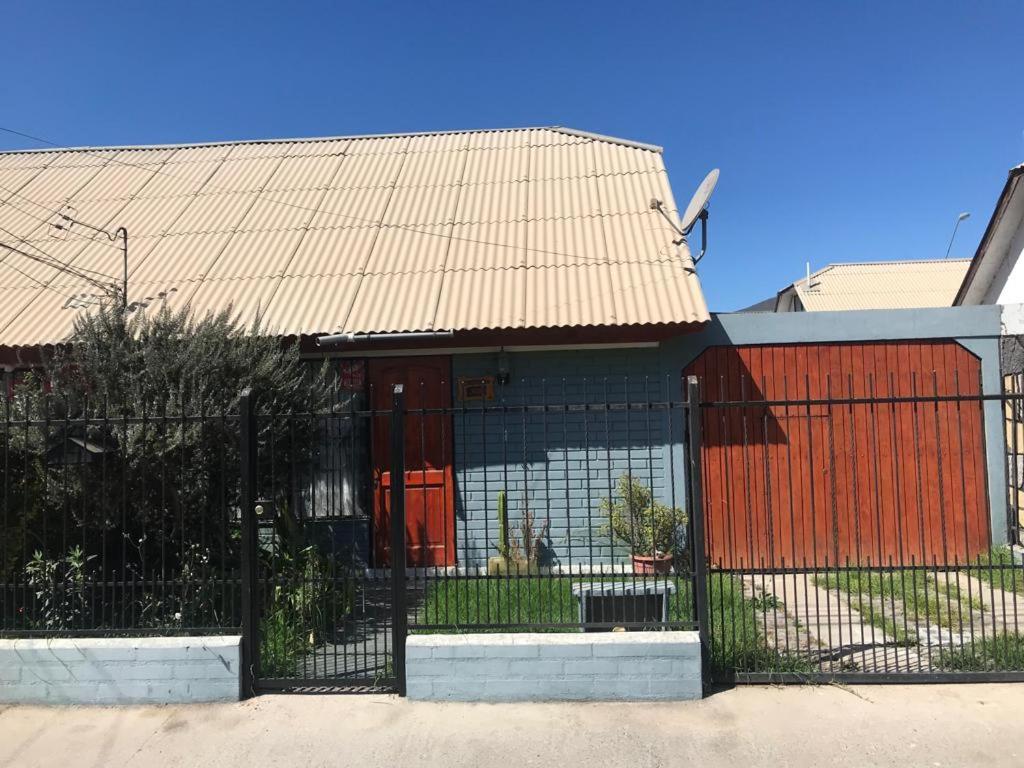 einen Zaun vor einem Gebäude mit einer roten Tür in der Unterkunft Casa full amoblada: 3 dormitorios + estacionamiento in Coquimbo