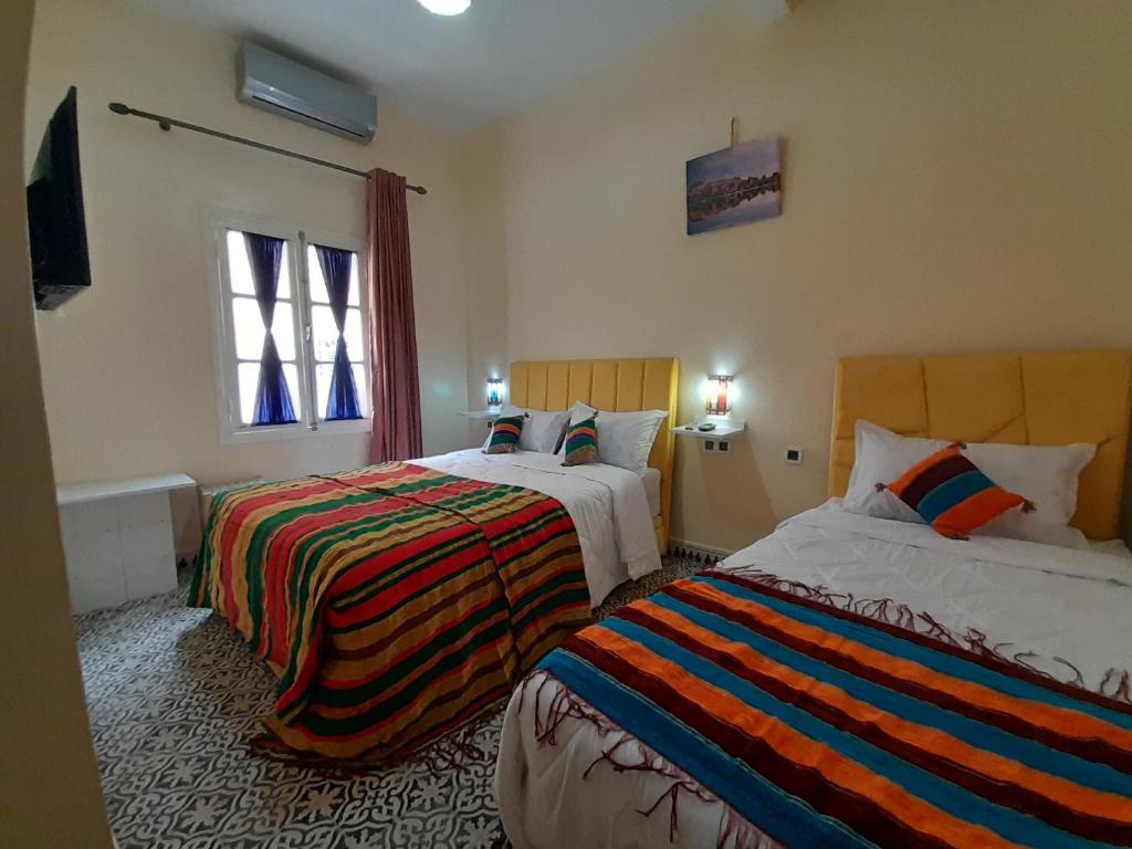 a bedroom with two beds and a window at Hotel Mentaga in Taroudant