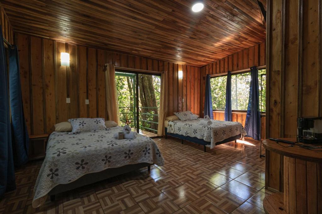 um quarto com 2 camas num quarto com paredes de madeira em The Green Tree Lodge em Monteverde