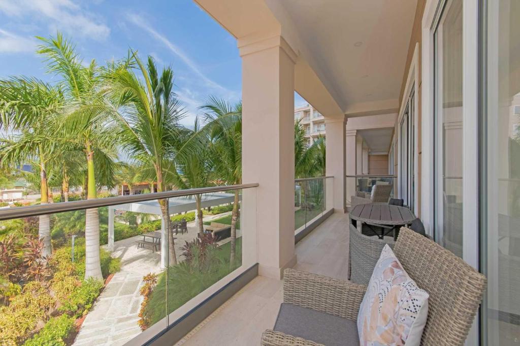 d'un balcon avec une table, des chaises et des palmiers. dans l'établissement Larimar Delights Three-bedroom condo, à Palm-Eagle Beach