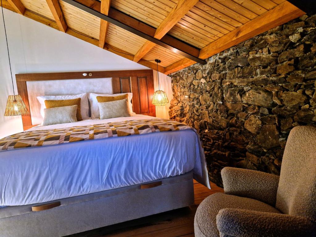 1 dormitorio con cama y pared de piedra en Sweet Côa, en Sabugal