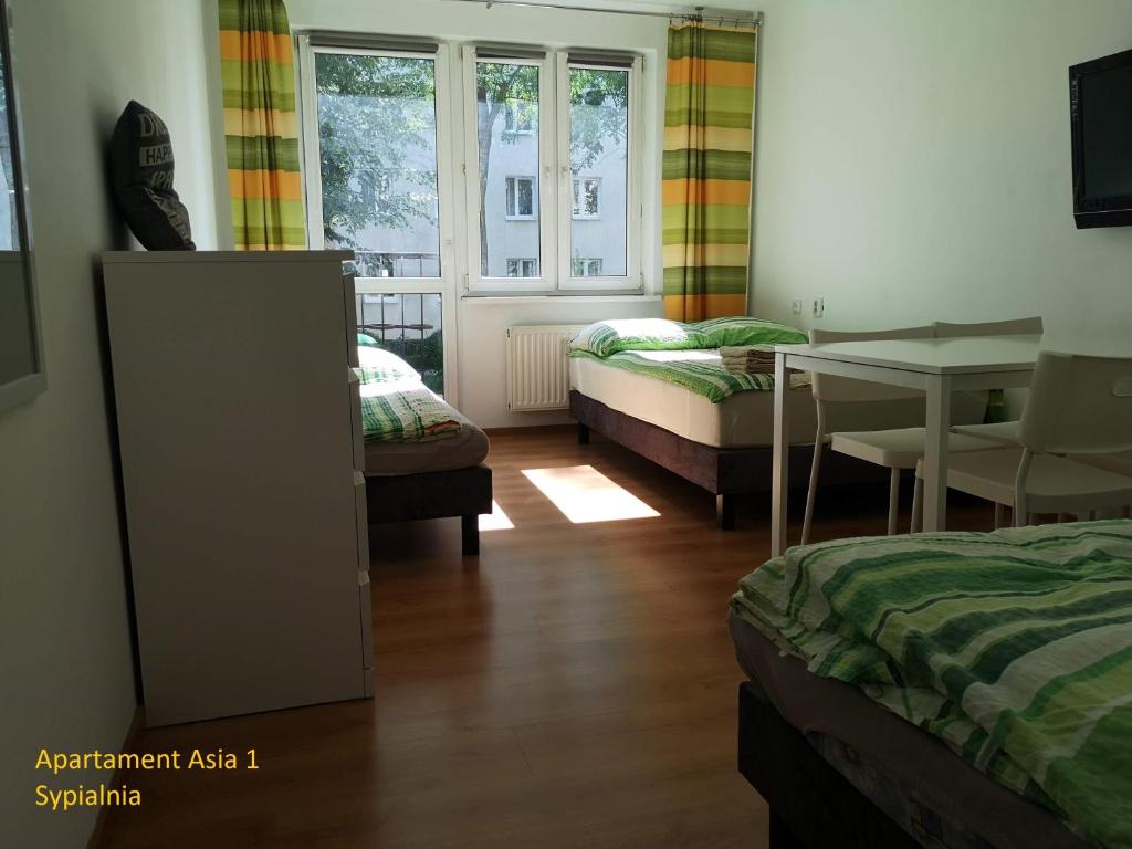 克拉科夫的住宿－Apartamenty Asia Kraków，客房设有两张床、一张桌子和一张书桌。