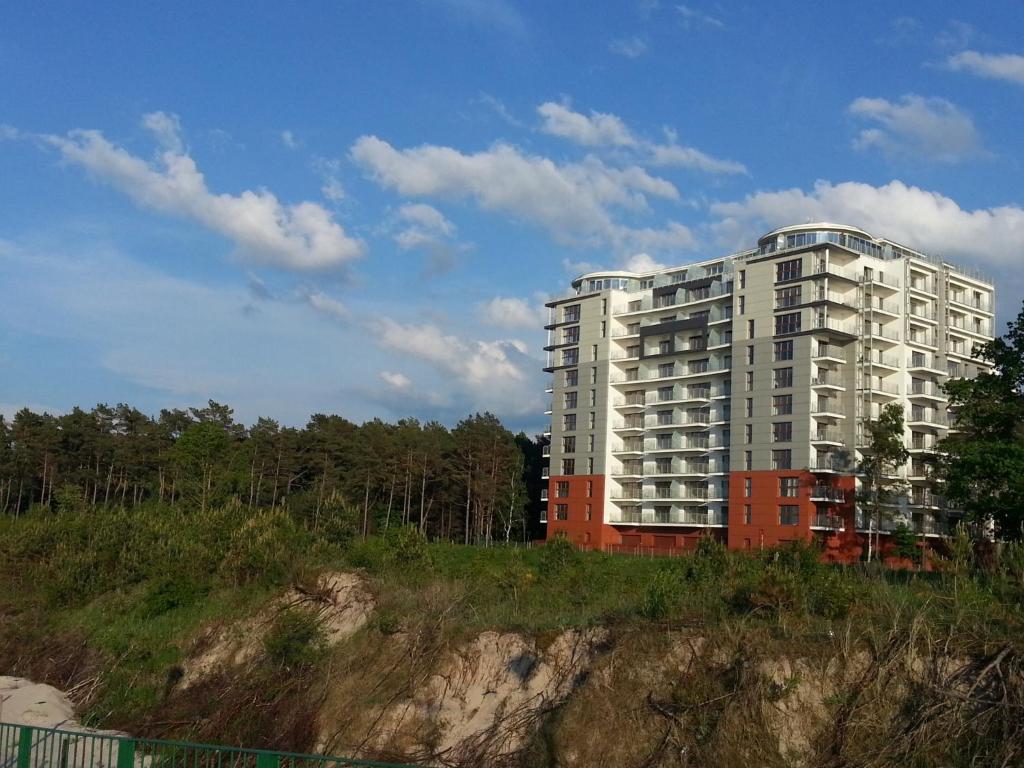 a tall white building on top of a hill at Porta Mare Apartments LuxView in Dziwnówek