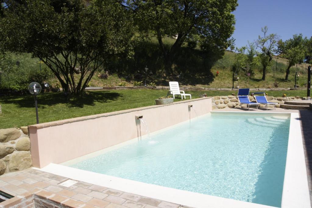 a swimming pool with two lawn chairs and two chairs at La Casa del Falegname in Umbertide