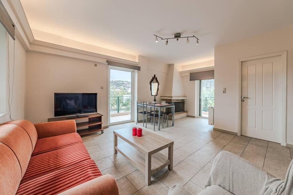 a living room with a couch and a television at George residence Attica Riviera in Kalívia Thorikoú