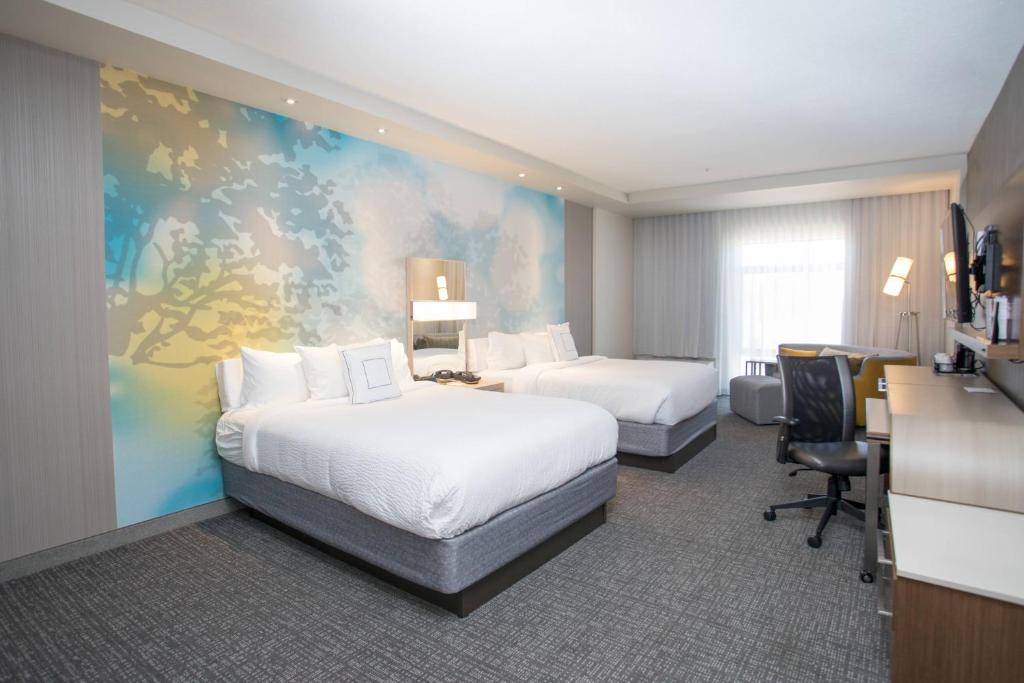 a hotel room with two beds and a desk at Courtyard by Marriott Albion in Albion