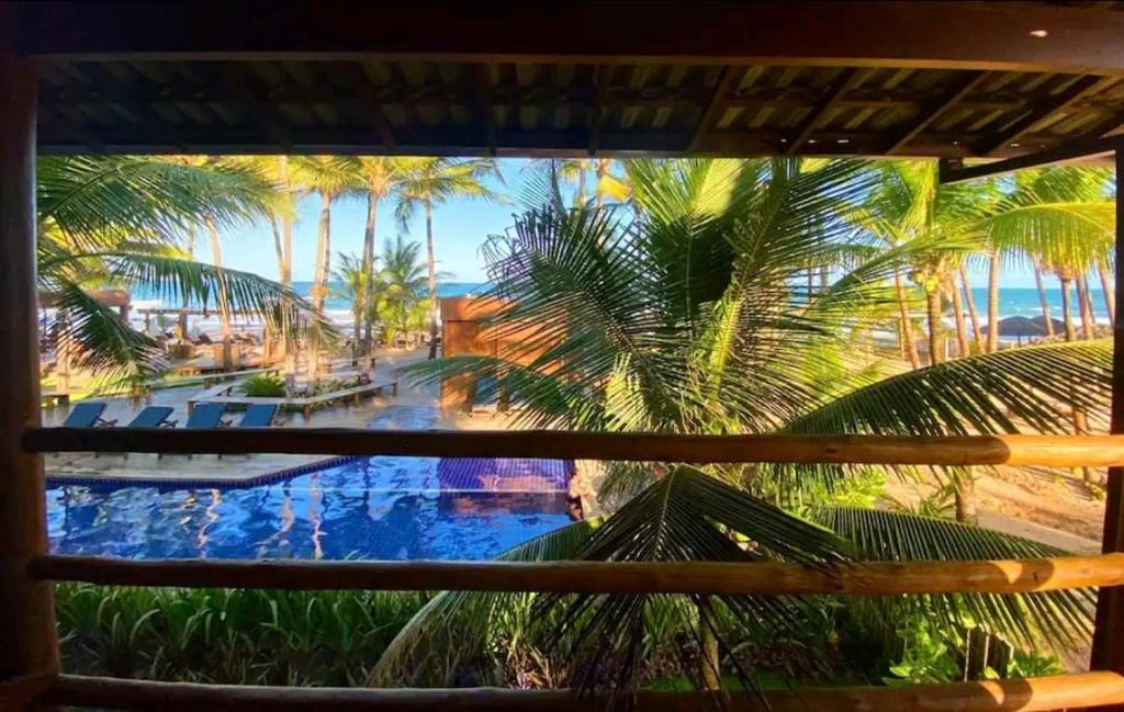 uma vista para uma piscina com palmeiras e para o oceano em 105 Condo Dreamland Apts BeachFront - Taipu de Fora em Marau