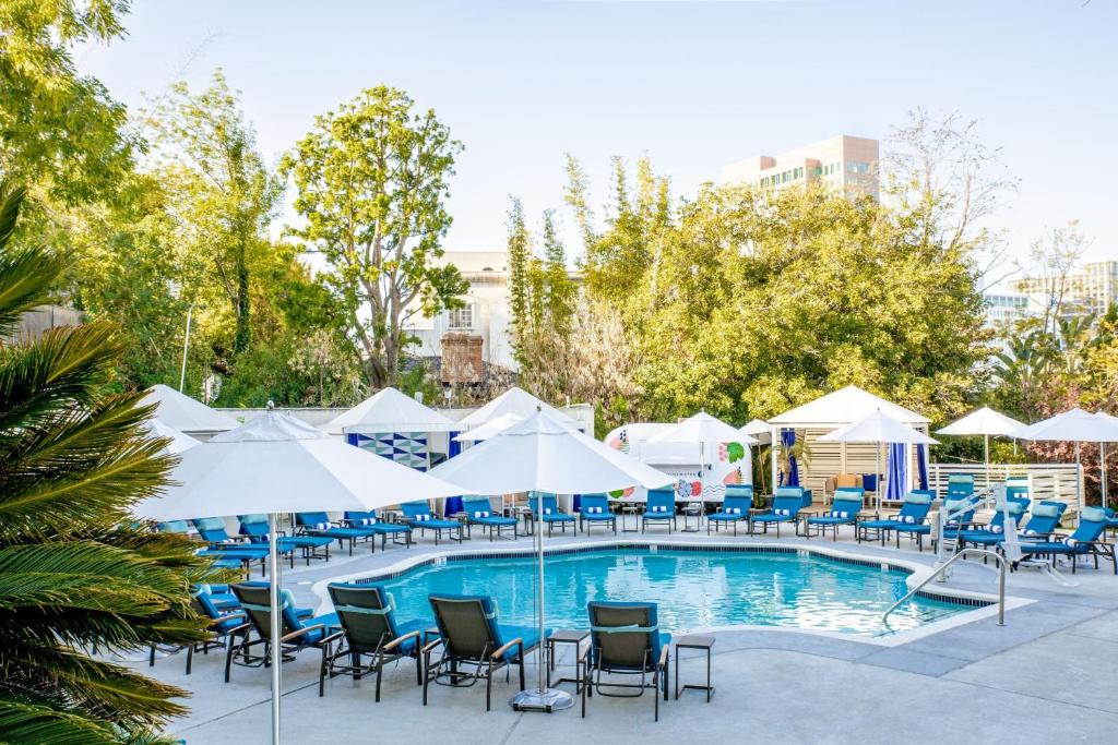 una piscina con sillas y sombrillas en W Los Angeles – West Beverly Hills en Los Ángeles