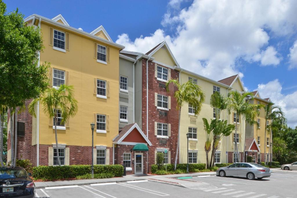 マイアミにあるTownePlace Suites Miami West Doral Areaの駐車場内のヤシの木が茂る大きな黄色の建物