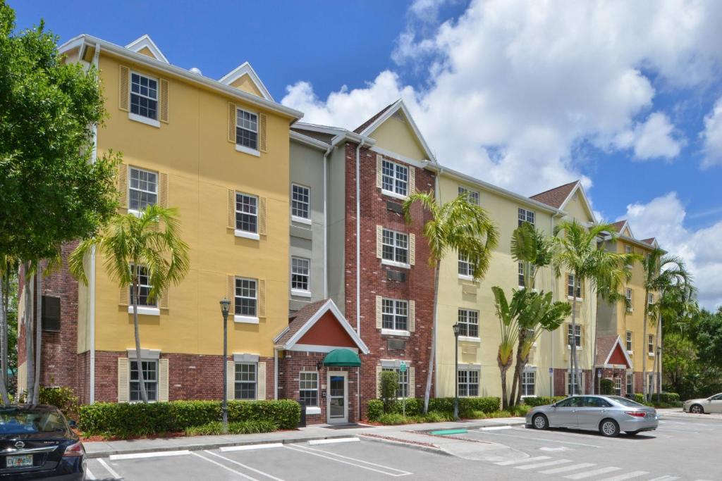 a large yellow building with palm trees in a parking lot at TownePlace Suites Miami West Doral Area in Miami