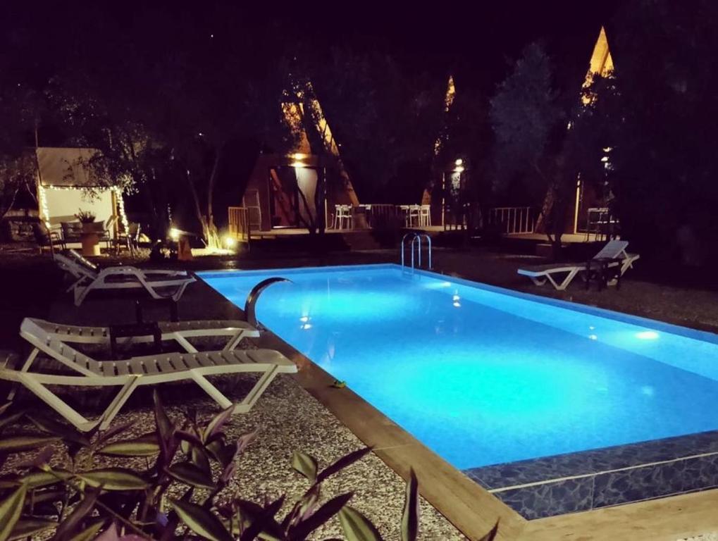 una piscina notturna con due sedie a sdraio intorno di GÖCEK BUNGALOW a Göcek