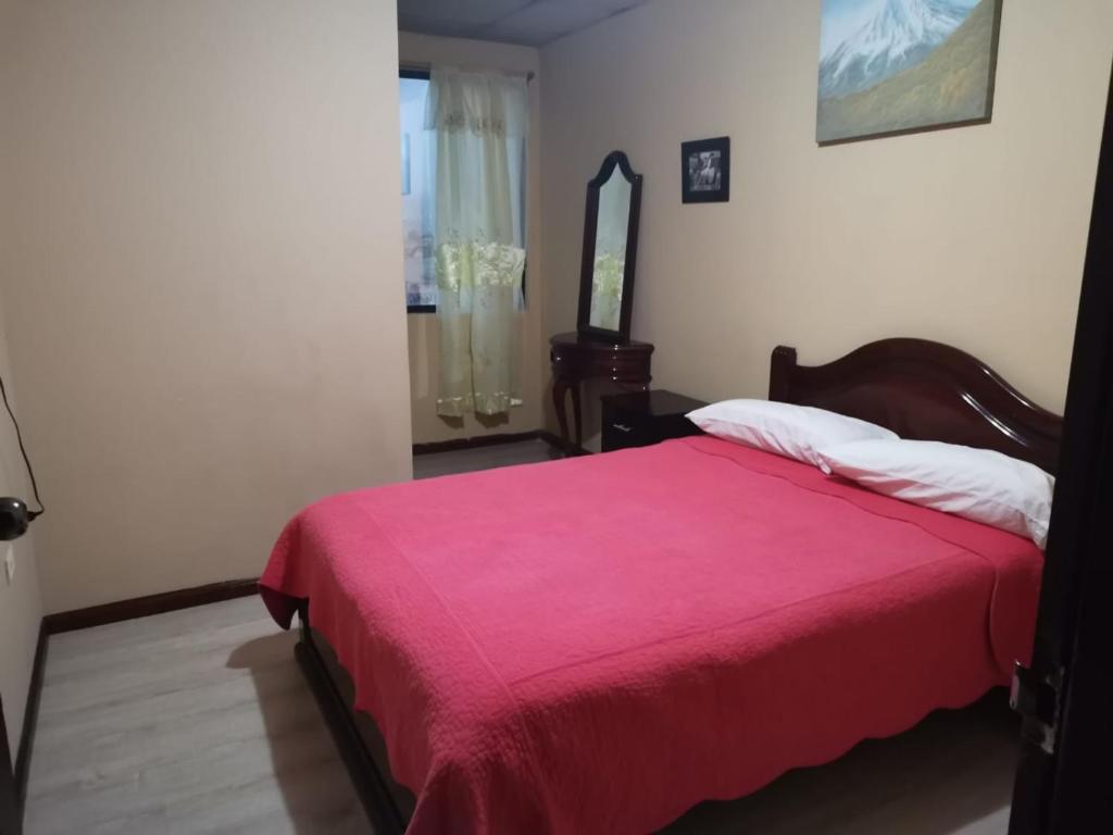 HOTEL 4 RIOS في كوينكا: غرفة نوم بسرير وبطانية حمراء ومرآة