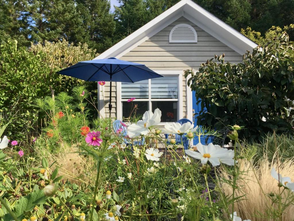 a house with a blue umbrella and some flowers at Belle Maison Auprès De La Mer in Sidney