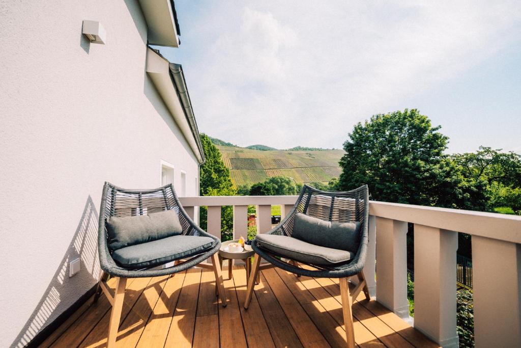 two chairs on a balcony with a view of the mountains at Gut Försterlay - Exklusive Boutique Apartments im historischen Winzerhaus direkt an der Mosel in Lösnich