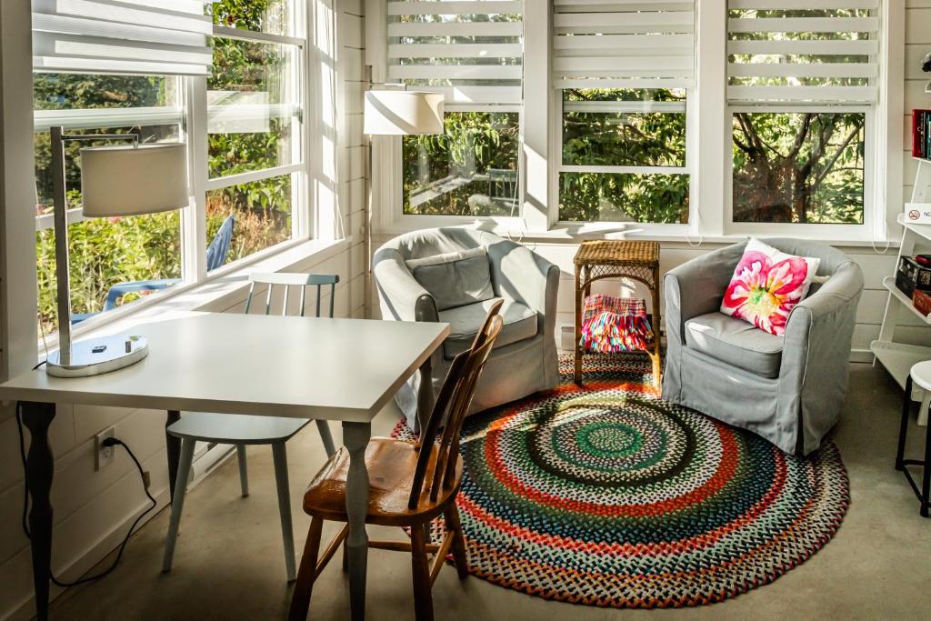 a living room with a table and chairs and windows at Belle Maison Auprès De La Mer in Sidney