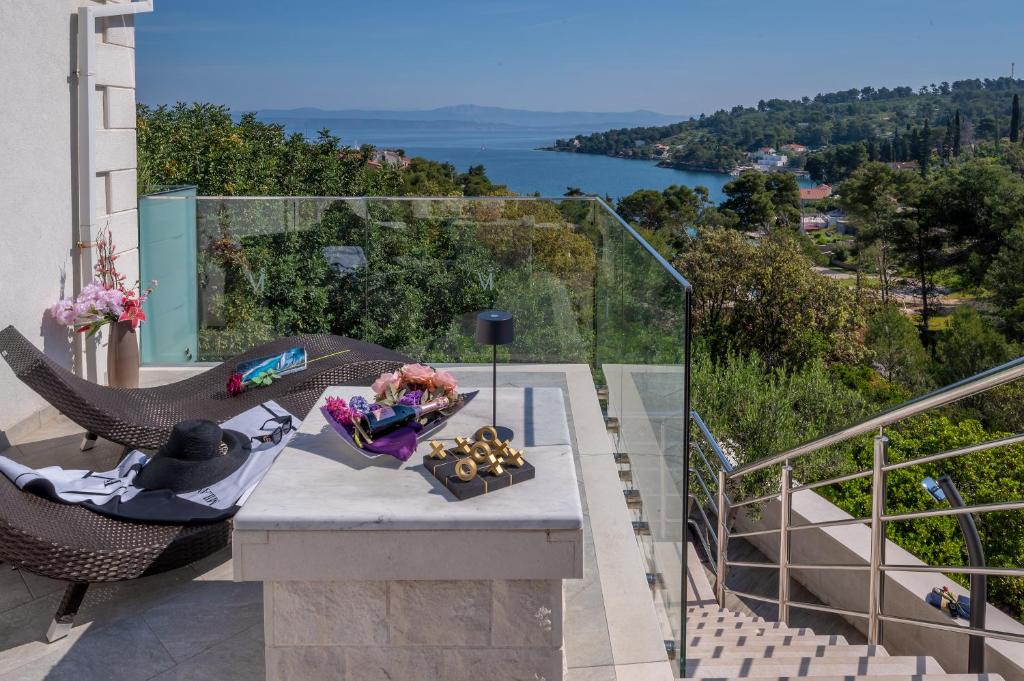 a table on a balcony with a view of a lake at Uniquely designed Villa Ivana with outdoor Jacuzzi nearby the pebble Banje beach at the Island of Solta in Rogač