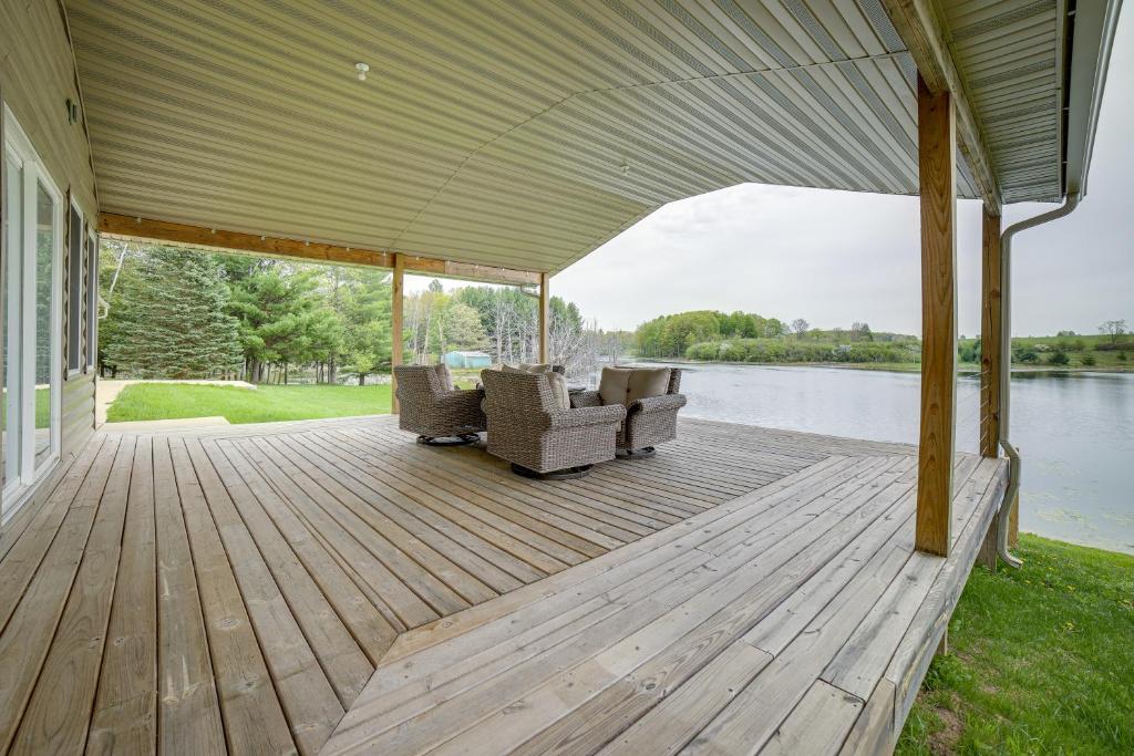 a covered deck with chairs and a view of a lake at Secluded Evart Vacation Rental on 82 Acres! in Evart