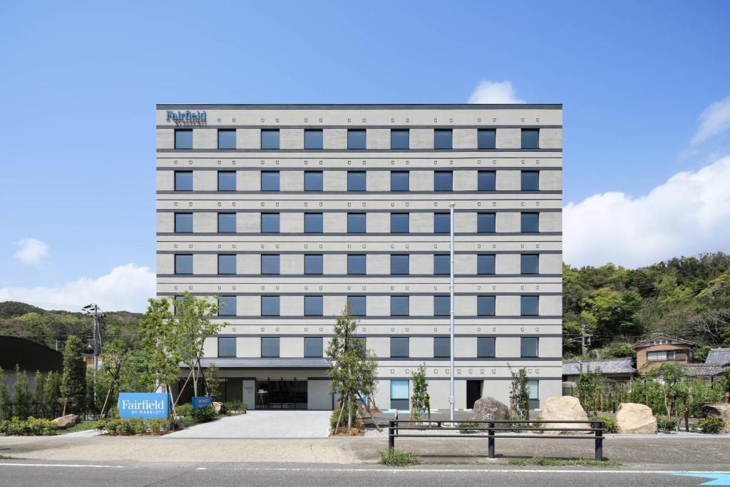 串本的住宿－Fairfield by Marriott Wakayama Kushimoto，一座高大的白色建筑,前面有长凳