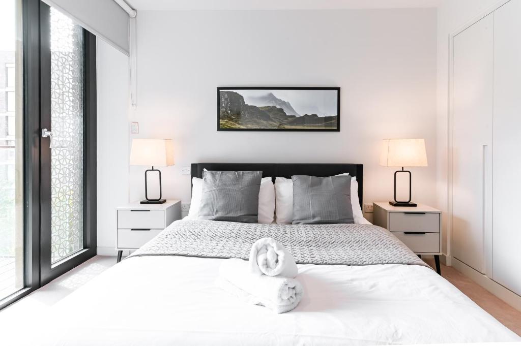 1 dormitorio con 1 cama blanca grande y 2 lámparas en Khayat Homes - The Canex - One Bed, en Londres