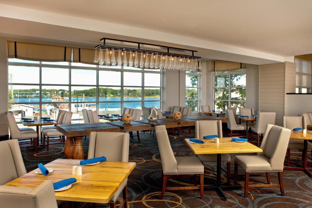 een restaurant met houten tafels en stoelen en een groot raam bij Sheraton Portsmouth Harborside Hotel in Portsmouth