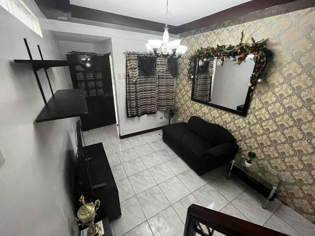 uma sala de estar com um sofá preto e um espelho em HOUSE FOR RENT IN LASPINAS em Manila