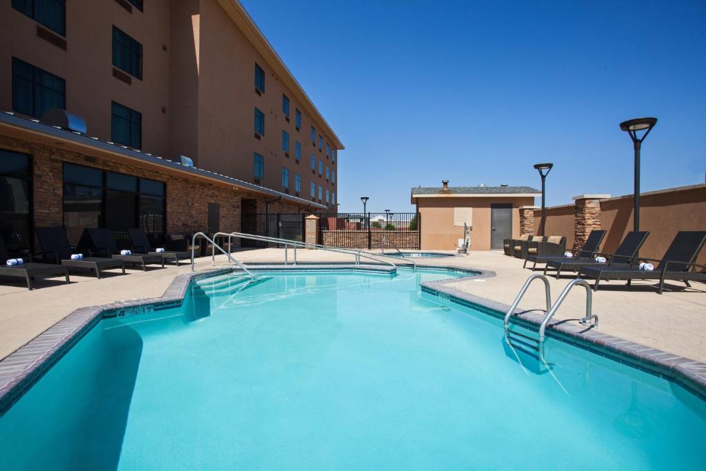 ein großer Pool mit Stühlen und ein Gebäude in der Unterkunft TownePlace Suites by Marriott Hobbs in Hobbs