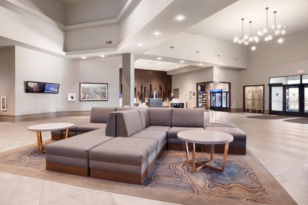 Delta Hotels by Marriott Fargo في فارغو: غرفة معيشة كبيرة مع أريكة وطاولات