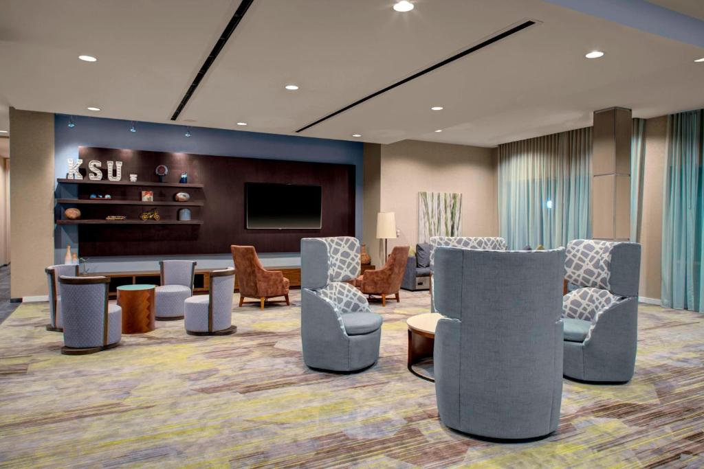 a lobby with a waiting room with chairs and a tv at Courtyard by Marriott Atlanta Kennesaw in Kennesaw