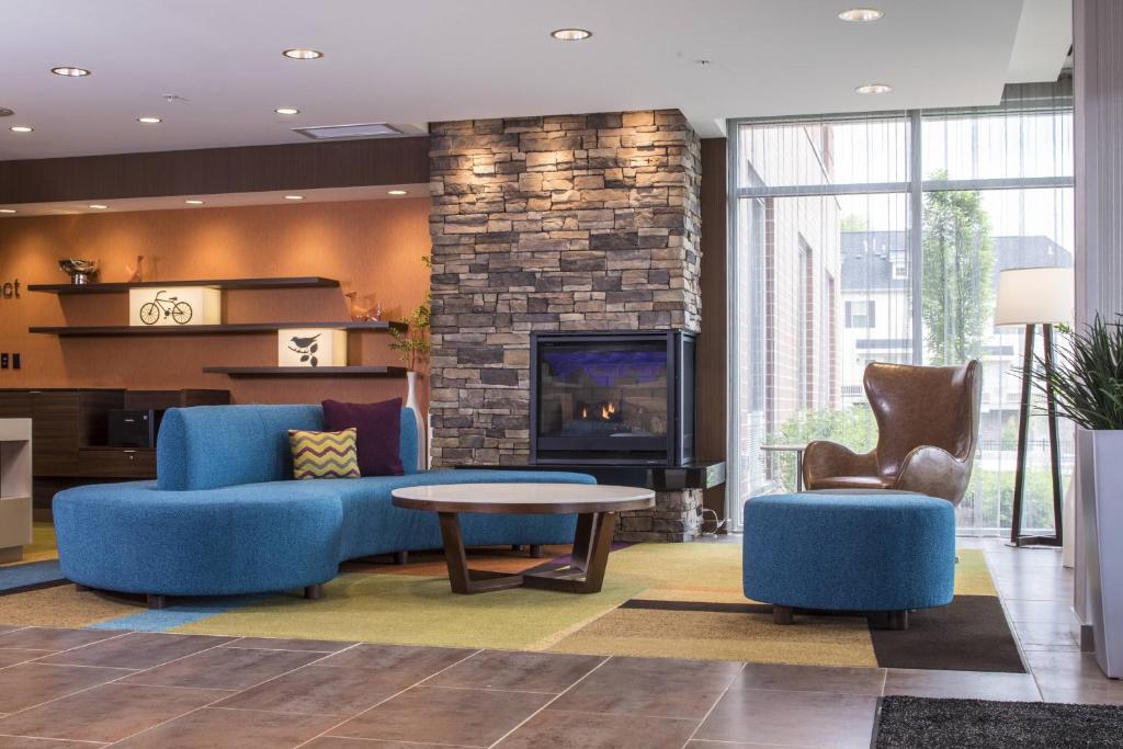 a living room with blue furniture and a fireplace at Fairfield Inn & Suites by Marriott Pittsburgh North/McCandless Crossing in McCandless Township