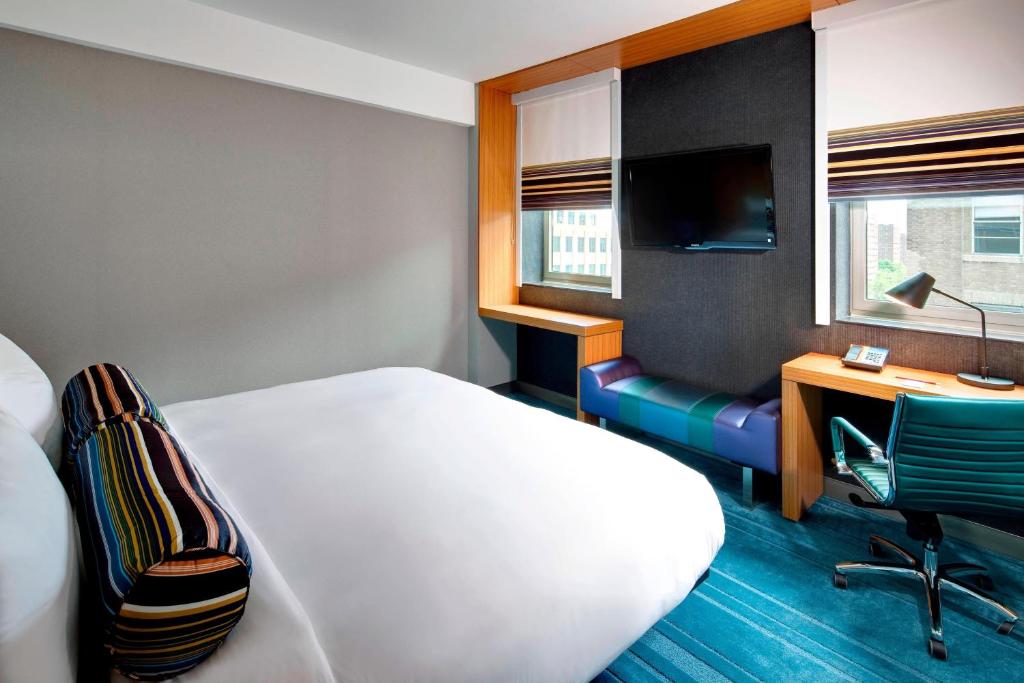 a hotel room with a bed and a desk with a computer at Aloft Brooklyn in Brooklyn