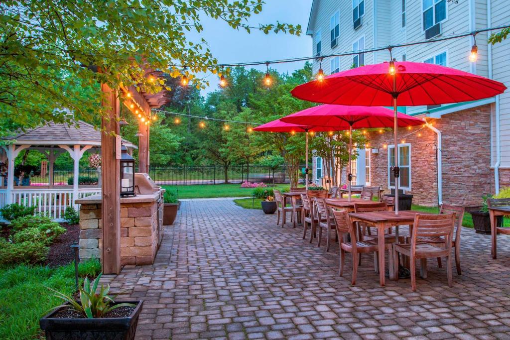 eine Terrasse mit Tischen, Stühlen und roten Sonnenschirmen in der Unterkunft TownePlace Suites by Marriott Clinton at Joint Base Andrews in Clinton