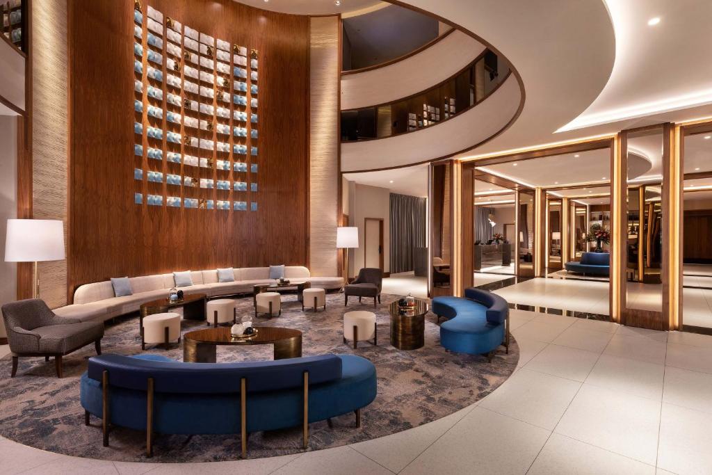 eine Lobby eines Hotels mit blauen Stühlen und Tischen in der Unterkunft Sheraton Grand Warsaw in Warschau