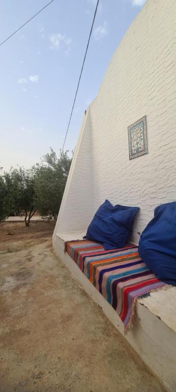 1 cama con mantas y almohadas de colores en un edificio en Typique appartement, en Houmt El Souk
