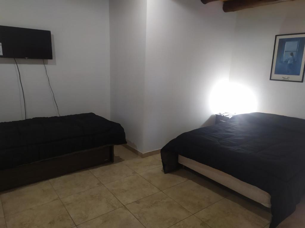 1 dormitorio con 2 camas y una luz en la pared en Departamentos Anchorena #5 en Luján de Cuyo