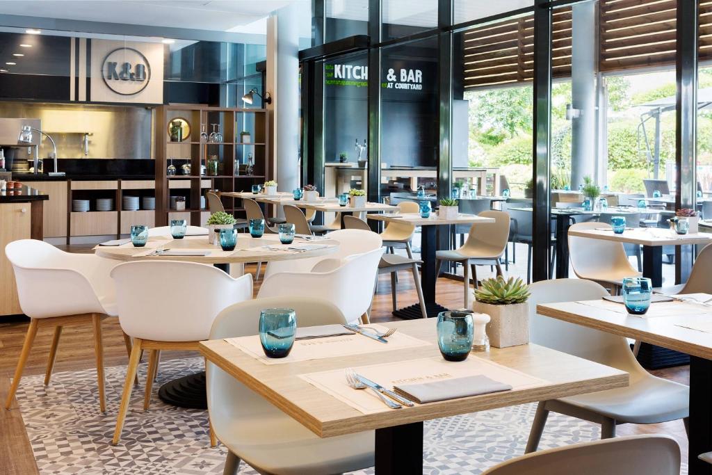a restaurant with wooden tables and white chairs at Courtyard by Marriott Toulouse Airport in Toulouse