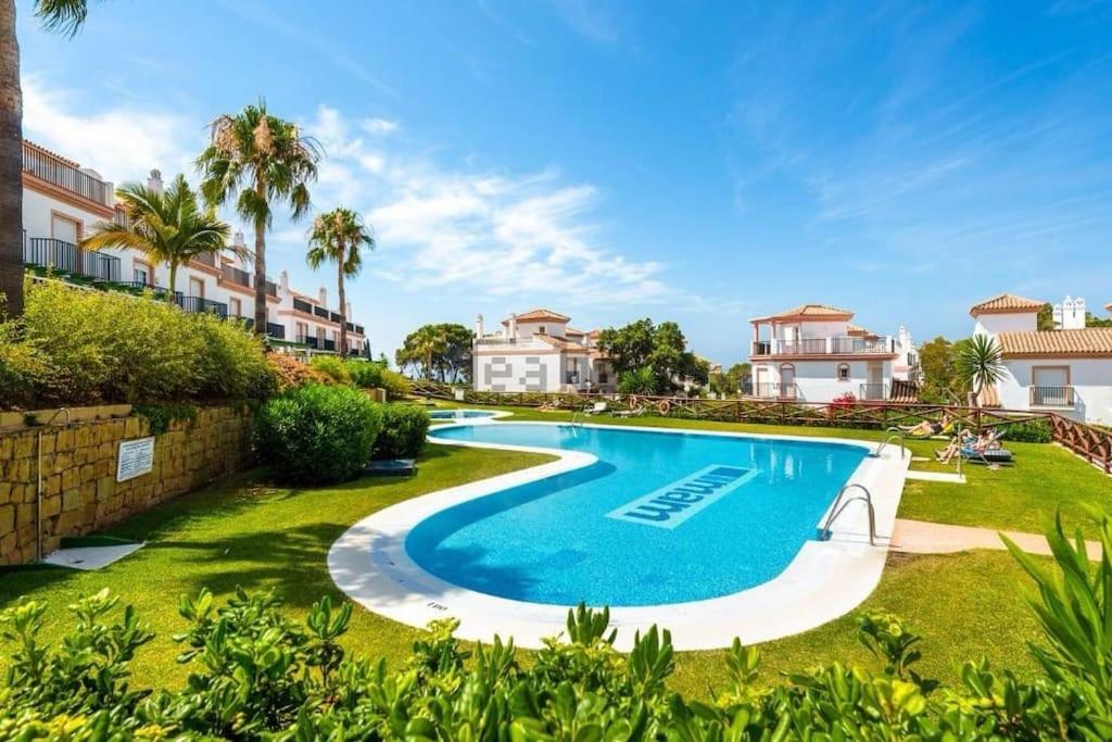 une image d'une piscine dans une cour avec des maisons dans l'établissement Jolie maison à Cabopino Marbella, à Marbella