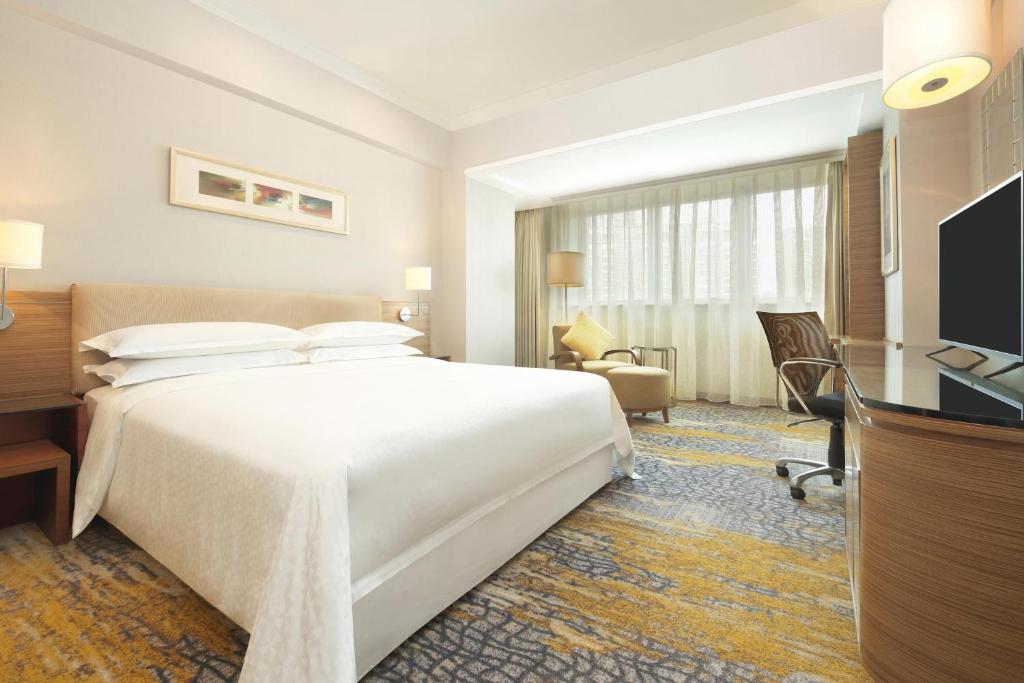 a hotel room with a large white bed and a desk at Four Points by Sheraton Shanghai, Pudong in Shanghai