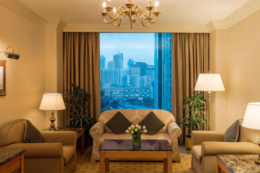- un salon avec une chaise et une grande fenêtre dans l'établissement Sheraton Kuwait, a Luxury Collection Hotel, Kuwait City, à Koweït