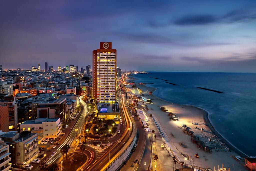 Sheraton Grand Tel Aviv في تل أبيب: مدينة ذات مبنى طويل والمحيط في الليل