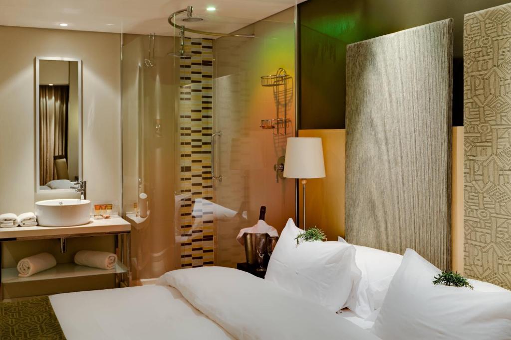 a bedroom with a bed and a bathroom with a shower at Protea Hotel by Marriott Bloemfontein Willow Lake in Bloemfontein