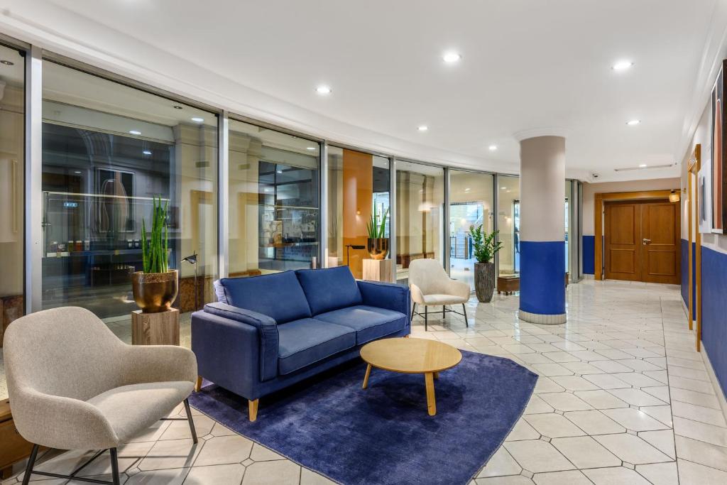 un vestíbulo con un sofá azul y sillas en Millennium Court, Budapest - Marriott Executive Apartments, en Budapest