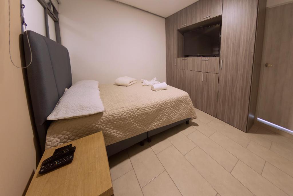 Habitación pequeña con cama y TV. en Ventiuna Hotel y Coliving, en Pereira
