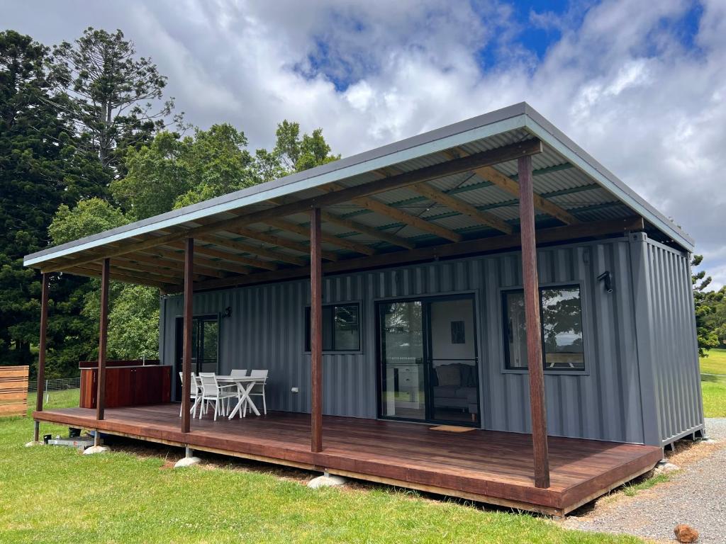 una casa pequeña con porche y terraza en Three Pines House - Unique Tiny House with Views en Mount Tamborine